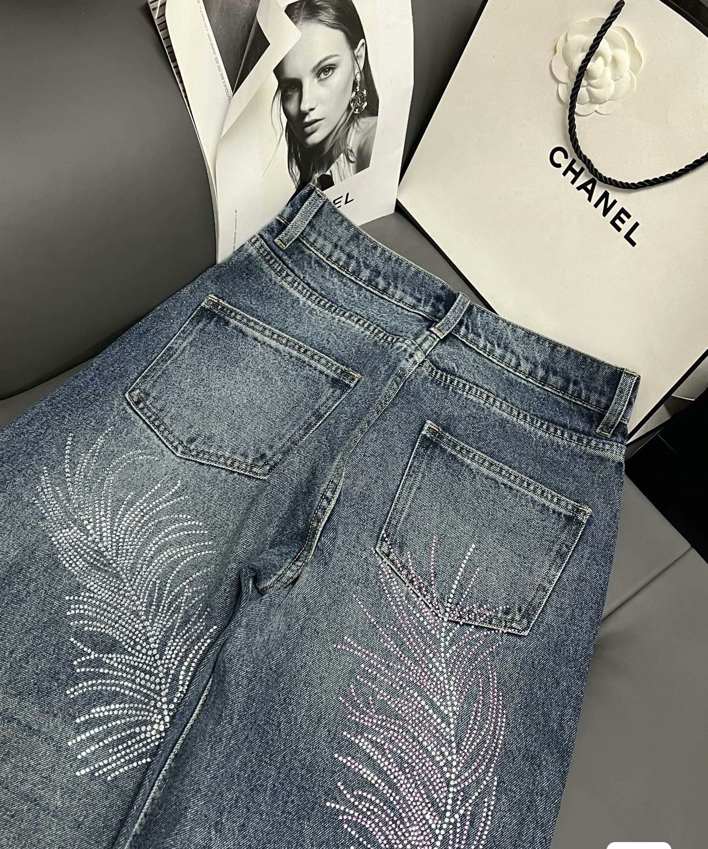 2026 Feather & Rhinestone Jeans: Featuring a high-waisted, wide-leg silhouette crafted from blue denim, with a unique feather and rhinestone embellishment design.
