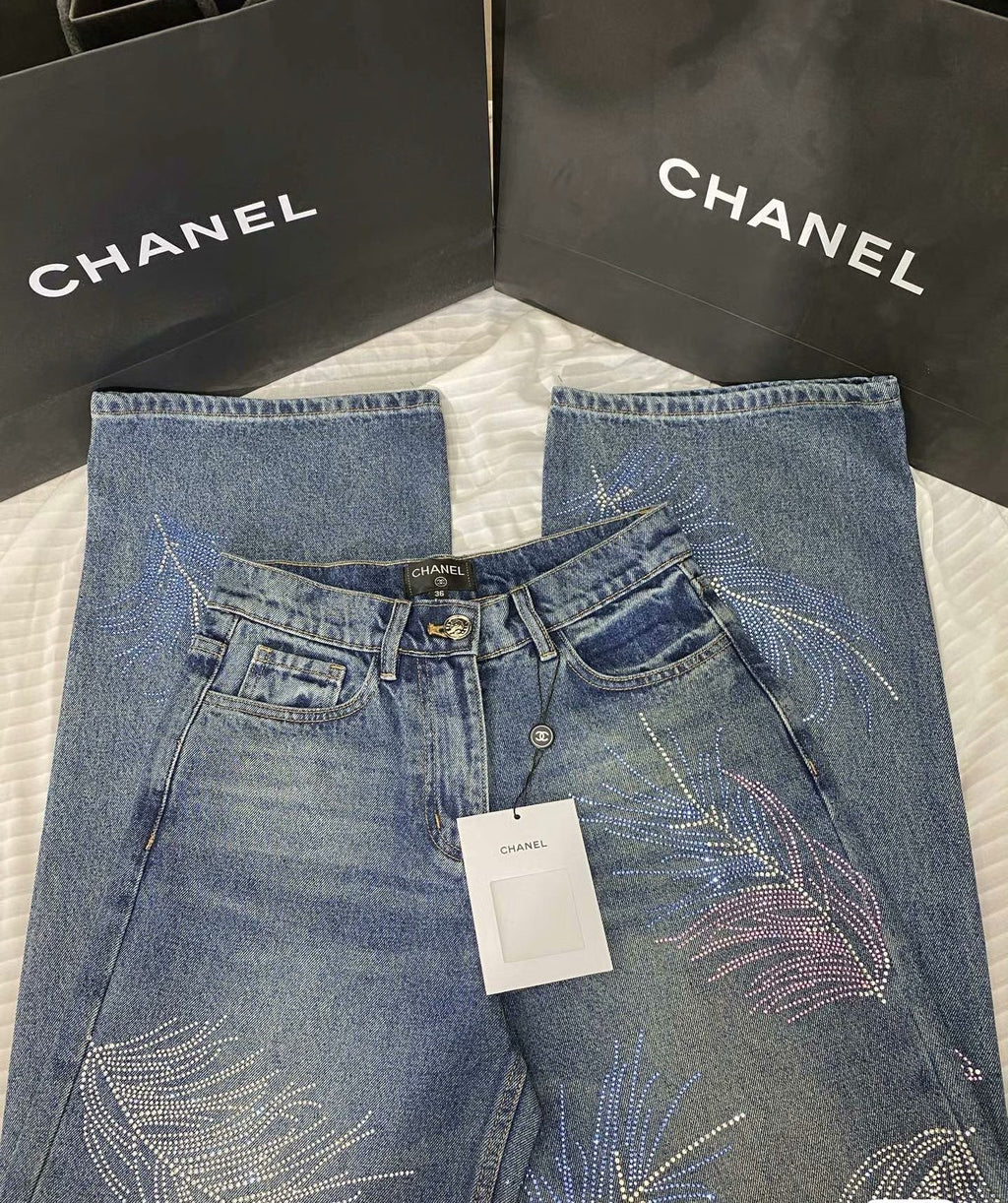 2026 Feather & Rhinestone Jeans: Featuring a high-waisted, wide-leg silhouette crafted from blue denim, with a unique feather and rhinestone embellishment design.