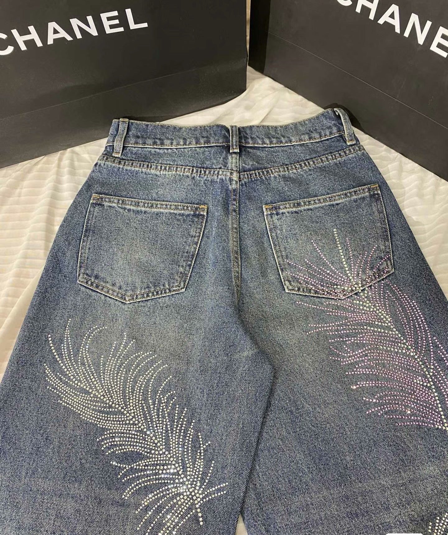 2026 Feather & Rhinestone Jeans: Featuring a high-waisted, wide-leg silhouette crafted from blue denim, with a unique feather and rhinestone embellishment design.